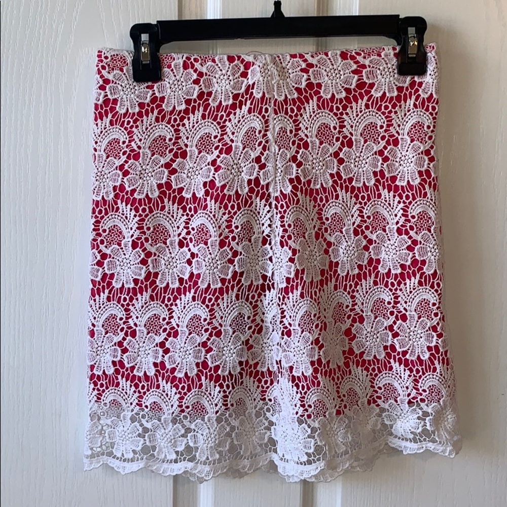 short pink skirt with white lace design over it.